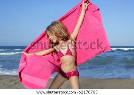 Beach little girl playing pink towel and wind in blue sea