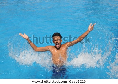 boy teenager splashing water open arms blue swimming pool