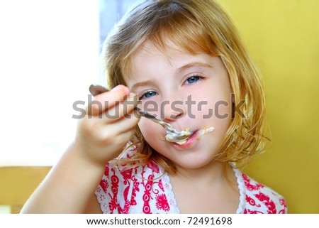 hungry little blond girl spoon eating ice cream pastry dirty mouth