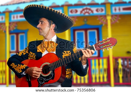 Charro Mariachi singer playing guitar in Mexico houses background [Photo Illustration]