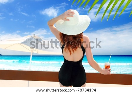 beach hat rear view woman cocktail tropical beach black swimsuit [Photo Illustration]