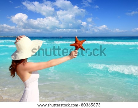 beach hat woman holding starfish with hand in a tropical turquoise sea