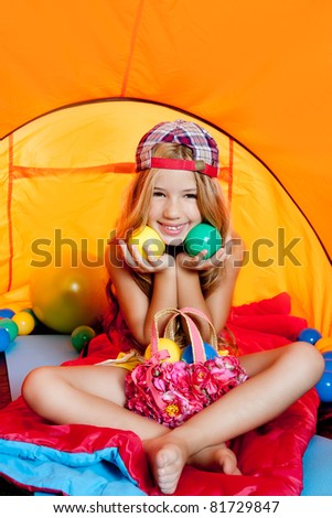 Children girl playing with balls inside camping tent smiling happy