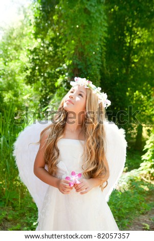 Angel children girl in forest holds flower in hand looking sky
