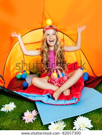 Girl playing with balls inside camping tent smiling happy