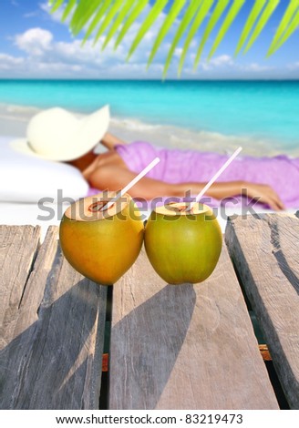 coconut cocktails with a woman sun tanning in topical Caribbean beach [Photo Illustration]