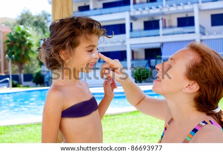 mother puts sunscreen cream in daughter face