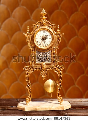 ancient vintage golden brass pendulum clock  in embossed background