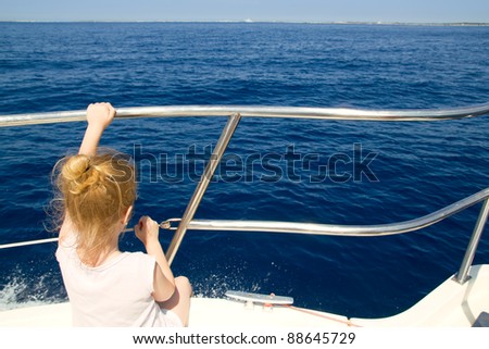 Blond little girl rear view sailing in boat in blue Ibiza sea