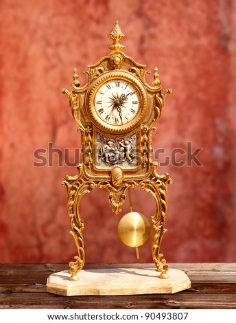 ancient vintage golden brass pendulum clock in red grunge background