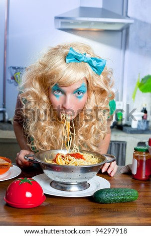 Blonde funny girl on kitchen eating pasta like crazy with blue makeup