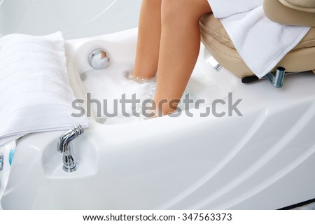 Pedicure feet bath in sofa chair woman at nails salon