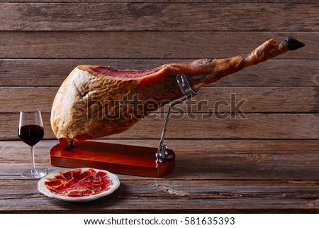 Iberian ham pata negra from Spain with red wine on wood background