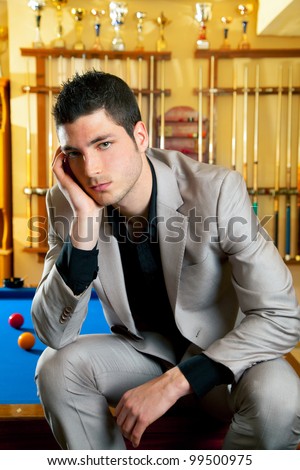 handsome man with suit sitting posing in billiard pool in club