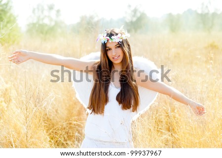 Angel ethnic woman in golden field with feather white wings and flowers crown