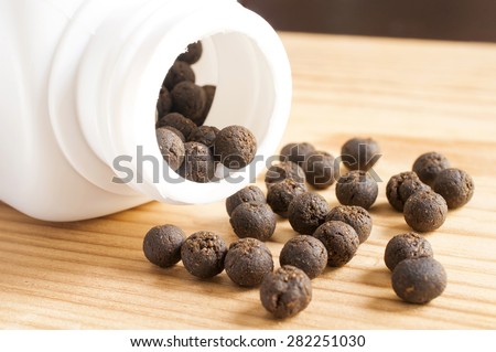 Thai herbal medicine, medicine ball spilling out of a bottle on wooden tray