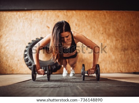 Woman works out her shoulders on the floor in gym