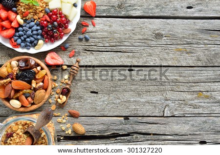 Ingredients for a healthy breakfast - berries, fruit, dried fruits and granola on the wooden background,  top view