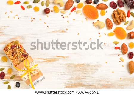 Homemade gluten free granola bars and mixed nuts, seeds, dried fruits on white wooden background. Copyspace background.Top view.