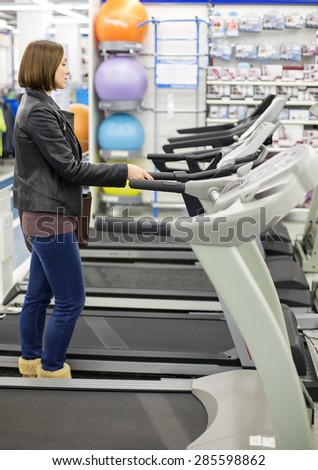woman buys a treadmill in a sports shop