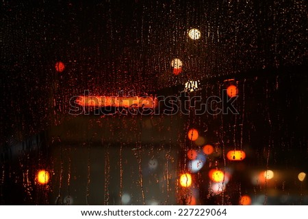 Wet the car window with the background of the night city traffic view.