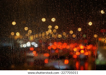 Wet the car window with the background of the night city traffic and  traffic congestion concept.