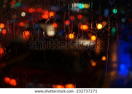 Wet the car window with the background of the night city traffic and traffic congestion concept.