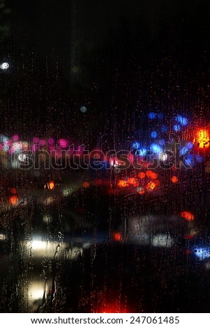 Wet the car window with the background of the night city traffic and traffic congestion concept.