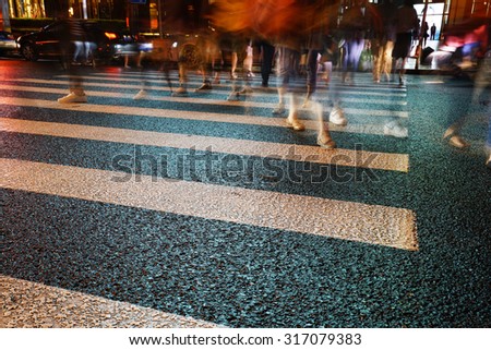 Night view of Crosswalk and pedestrian at modern city zebra crossing street in rainy day. Blur abstract.