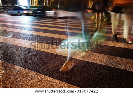 Night view of Crosswalk and pedestrian at modern city zebra crossing street in rainy day. Blur abstract.
