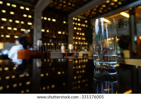 A glass of water on the table in lounge bar background.