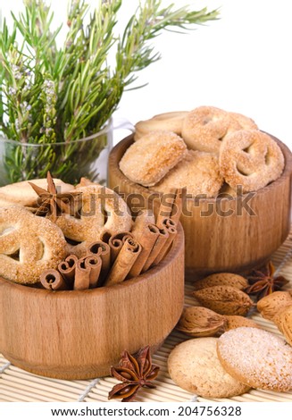 sweet sugar cookies in wooden containers with cinnamon sticks, almonds, anise asterisks, and a pitcher of rosemary