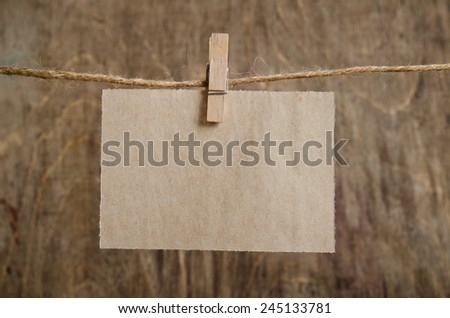 Old sheet of paper hanging on the clothesline on clothespin . On old wood background.