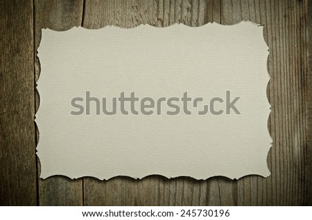 The piece of old white paper lying on a wooden background