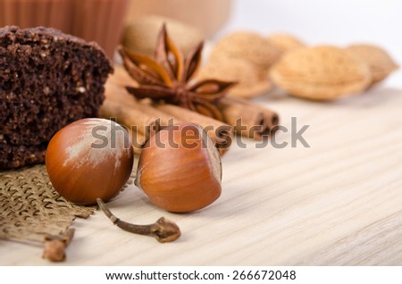 chocolate cake with nuts and cinnamon stick, star anise on wooden table