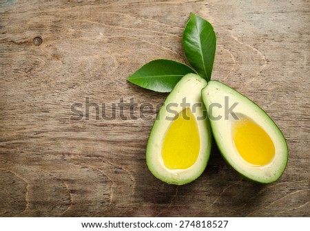 fresh two halfs of avocado like a bowl for oil on wooden background. top view