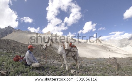 Sherpa and his horse rest on the high passes whilst trekking enroute to Zanskar, Ladakh, a high altitude desert CIRCA 2015