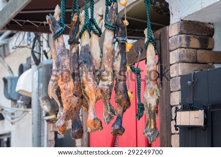 Some roasted legs of ham hanging outside a small shop in an alleyway in the countryside of Japan.
