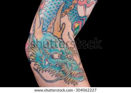 A detailed shot of a blue/green dragon tattoo in Japanese style on the forearm, elbow and bicep of a white male isolated on a black background.