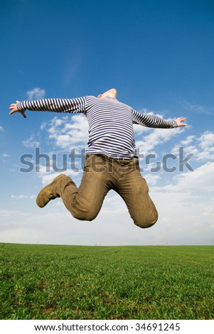 Young jumping man in the green field