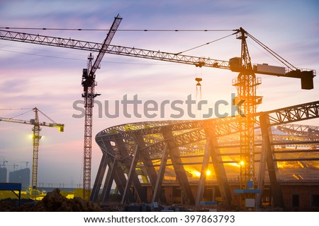 Lots of tower cranes build large residential buildings at night.