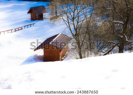 Small wooden 	lodge located in the snow in mountainous terrain.