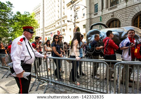 NEW YORK - JUNE 15:  New Yorkers and Tourist wait in line to take a picture of The Wall Street Bull Statue in Bowling Green Park June 15, 2013 in New York City.