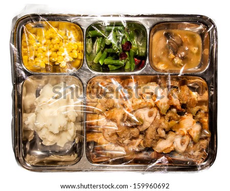 Old fashioned Thanksgiving TV dinner on metal tray covered in plastic