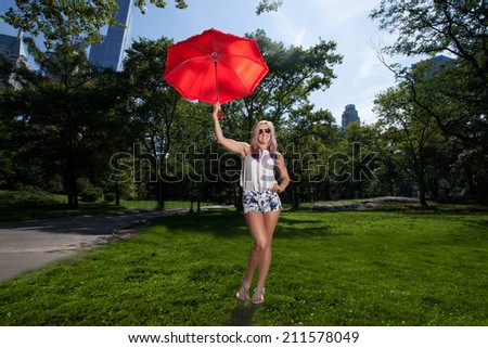 Young Blonde Athletic woman holding a Red Umbrella in Central Park