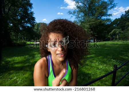 Young Brunette Hispanic woman wearing broken glasses and making silly faces in Central Park, NYC
