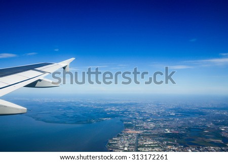 looking out of window while an airplane\'s flying above city and sea