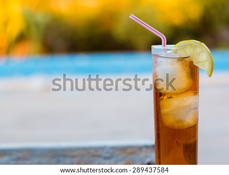 Ice tea with straw and lemon in a swimming pool