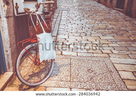 Red bicycle on a street of an old mediterranean town. Tinted and instagram filtered photo. Urban background.