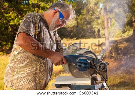Active Older Man Working with an Electric Saw in the Yard.